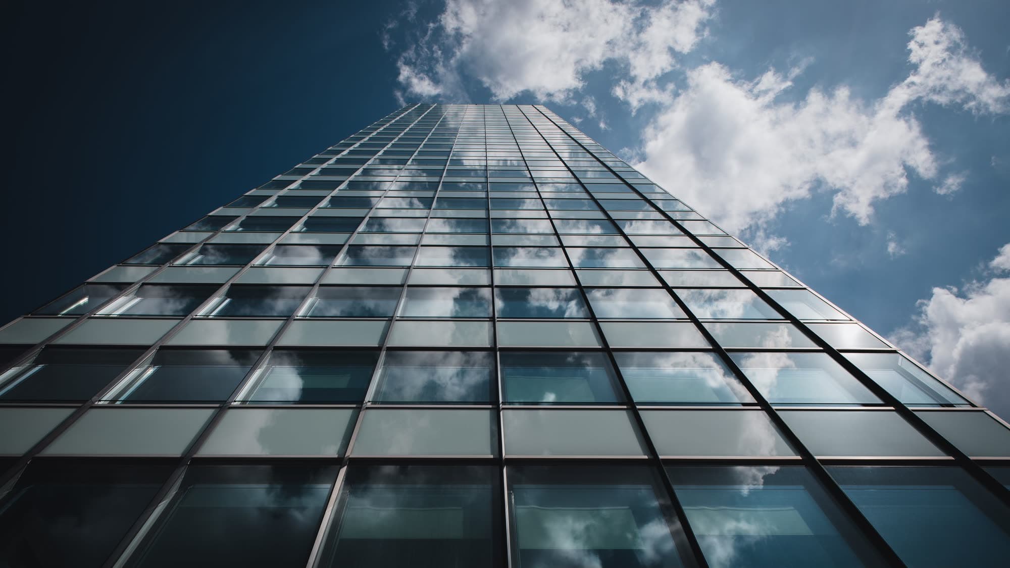 A glass tower rising into a bright sky